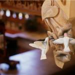 Handcarved humingbirds at the bottom of a staircase newel post