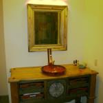Bathroom vanity custom built to fit wicker basket drawers with a vessel sink and unique faucet. Distressed knotty pine top completes the furniture look.
