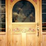 Carved entry door with wild rose motif and curved glass insert