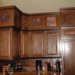 Solid cherry cabinets with hammered copper and gouged raised panel inserts and hammered copper backsplash