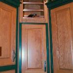 Small carved wine rack sits above corner cabinet